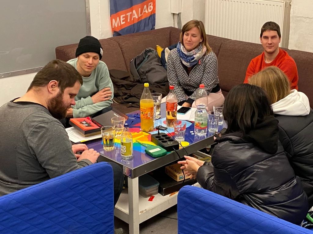 Define Jugend-Workshop 4, Gruppenbild im Weltraum des metalab. Sechs Jugendliche sitzen auf Sofas um einen Couch-Tisch herum. Am Couch-Tisch liegt ein Steckdosenverteiler und stehen Getränke. Im Hintergrund an der weißen Wand ist Banner mit der Aufschrift METALAB.